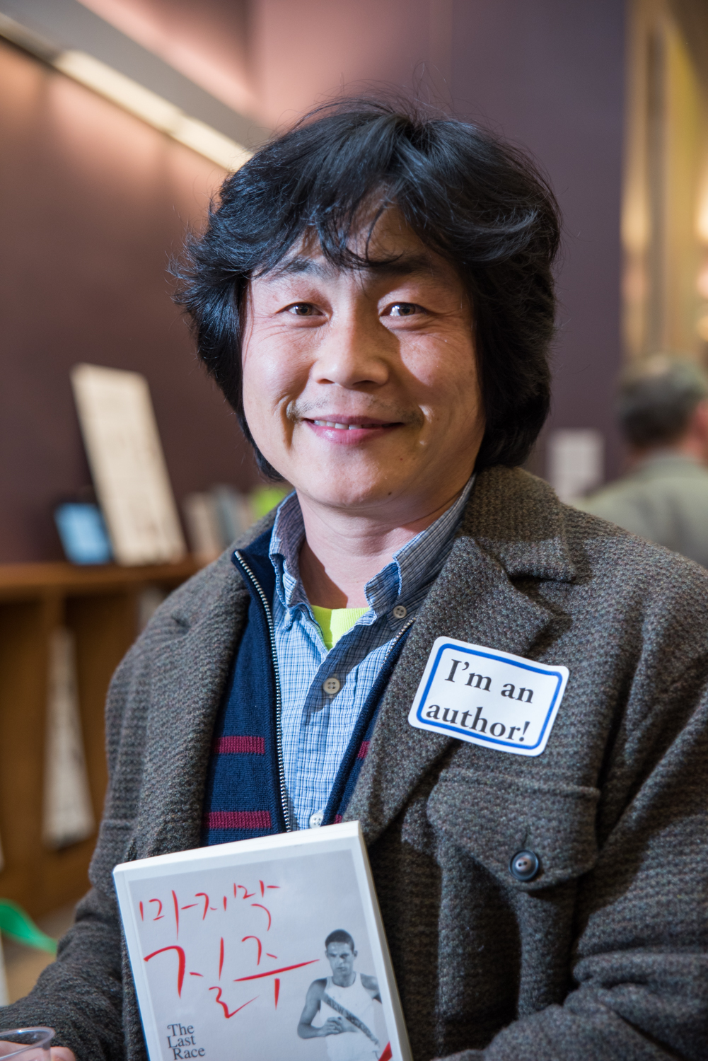 Dr. Kwon wearing a name tag that says "I'm an author!" and holding a book.