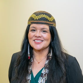 Headshot of Dr. Cutcha Risling Baldy wearing a traditional basket cap and shell necklaces