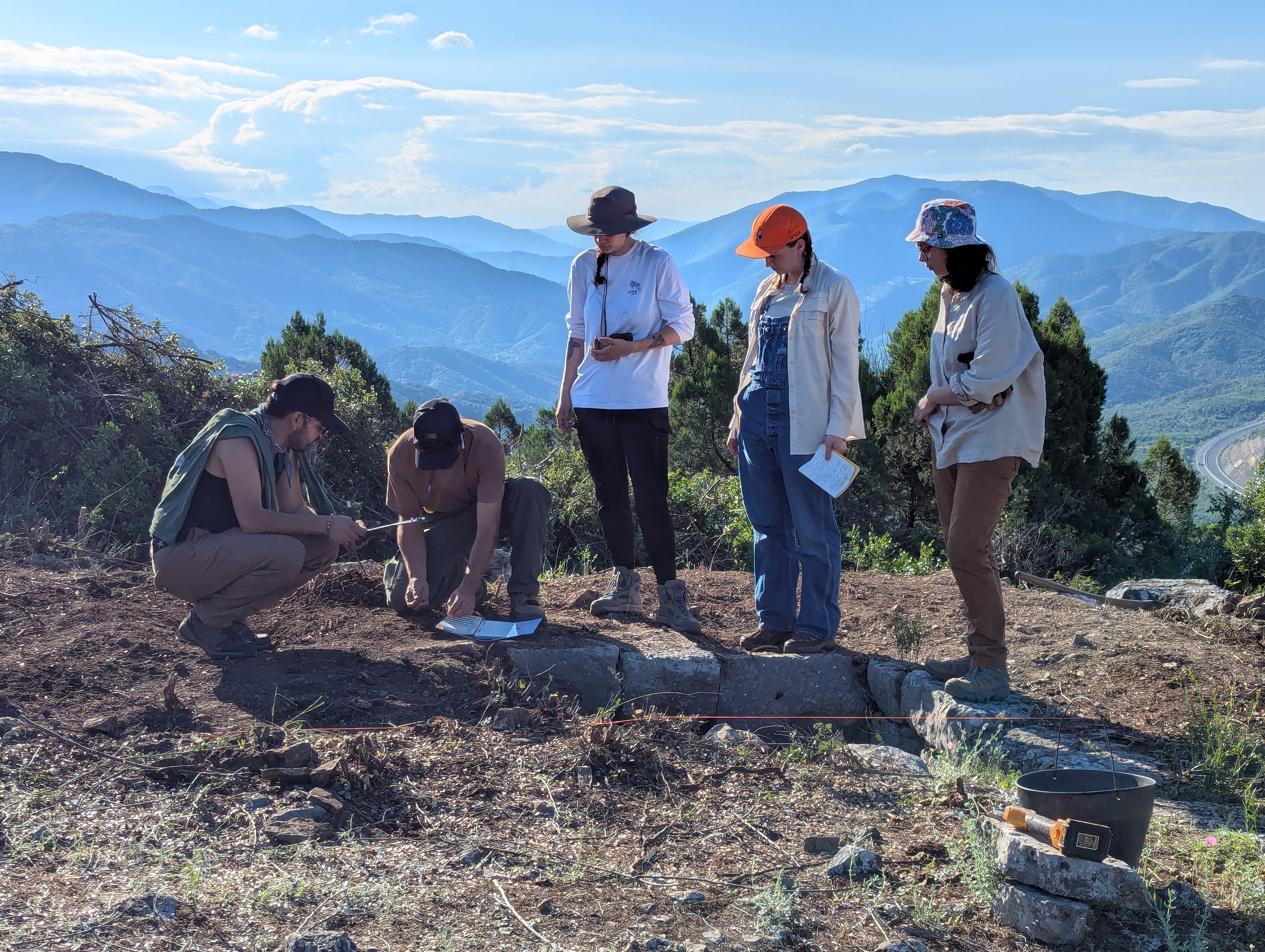 Five people outside working at an archaeological site