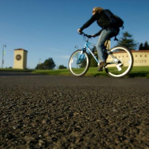 Student on a bike in front of the monument sign