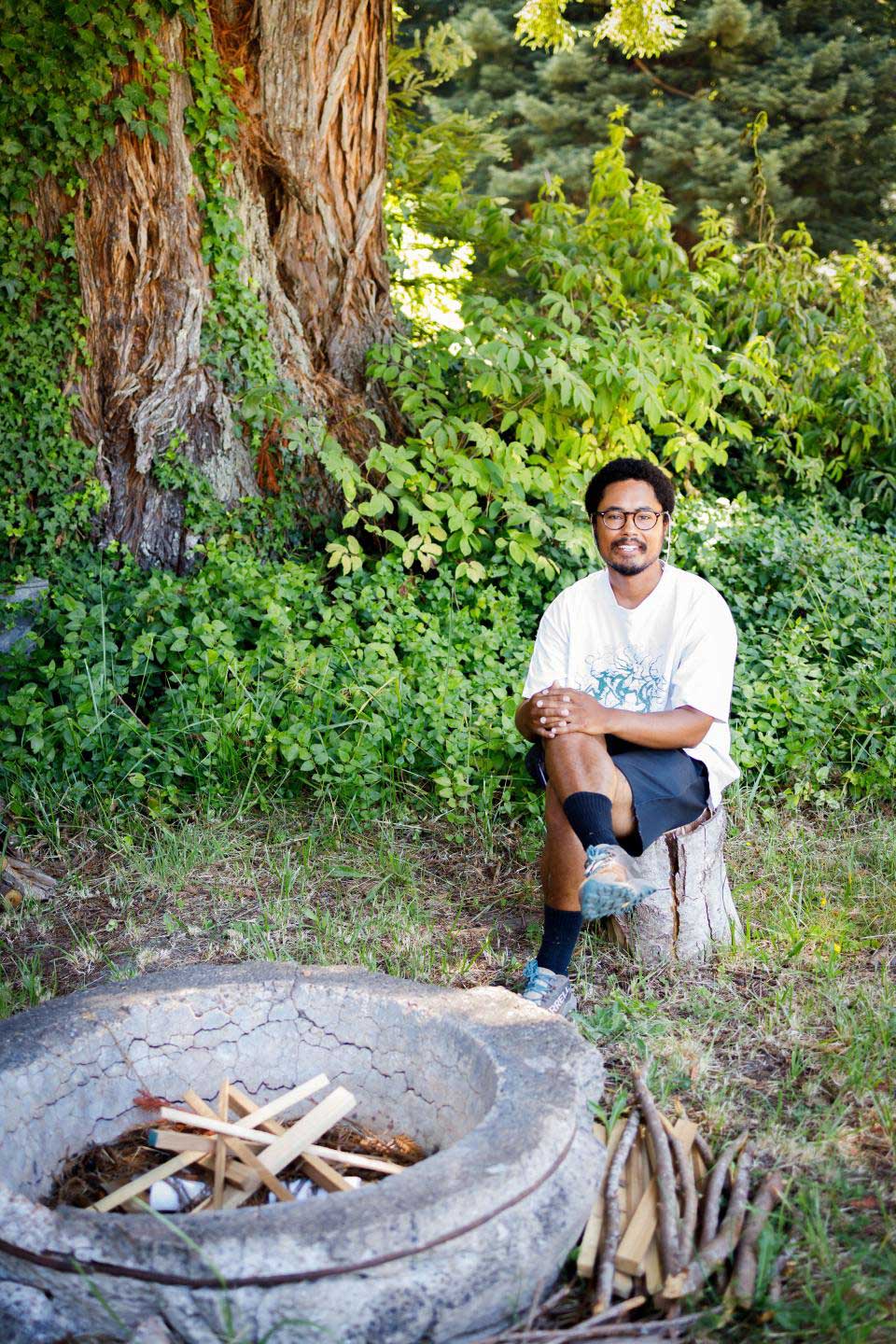 Kyle Buchanan sitting on log by a fire pit