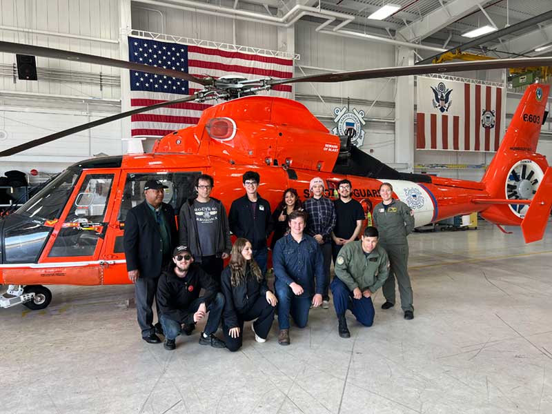 Group of people posing in with Coast Guard helicopter