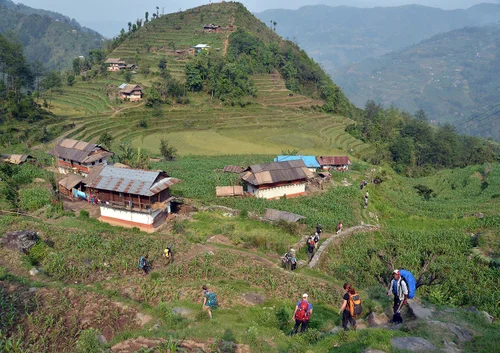 A group of hikers descend into basecamp on a lush green mountaintop.