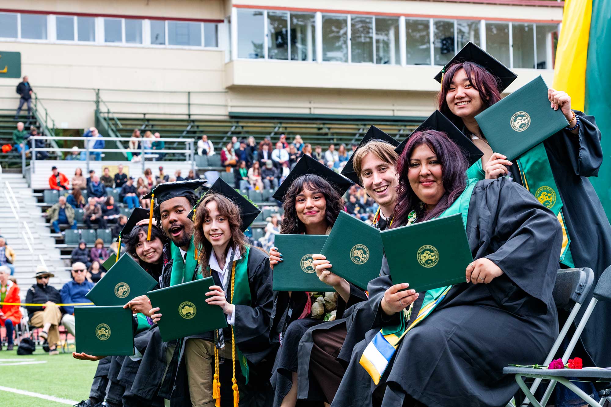 Spring graduates holding diplomas