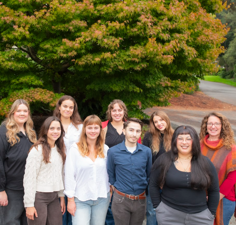 Team of Practicum students smiling for the camera standing in front of a large tree