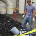 Person standing in front of a pile of tires with a bucket and yellow caution tape
