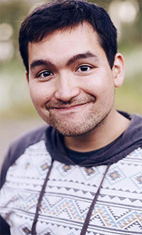 Ahron portrait, up close, wearing a whit shirt with patterns on it