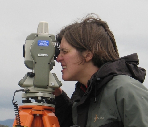 profile view of Maggie looking through some equipment with one eye squinted