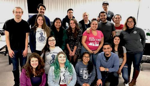 a diverse group of people standing together smiling for the camera