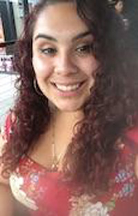 Tanya portrait, closeup, dark curly hair and a floral shirt, smiling for the camera
