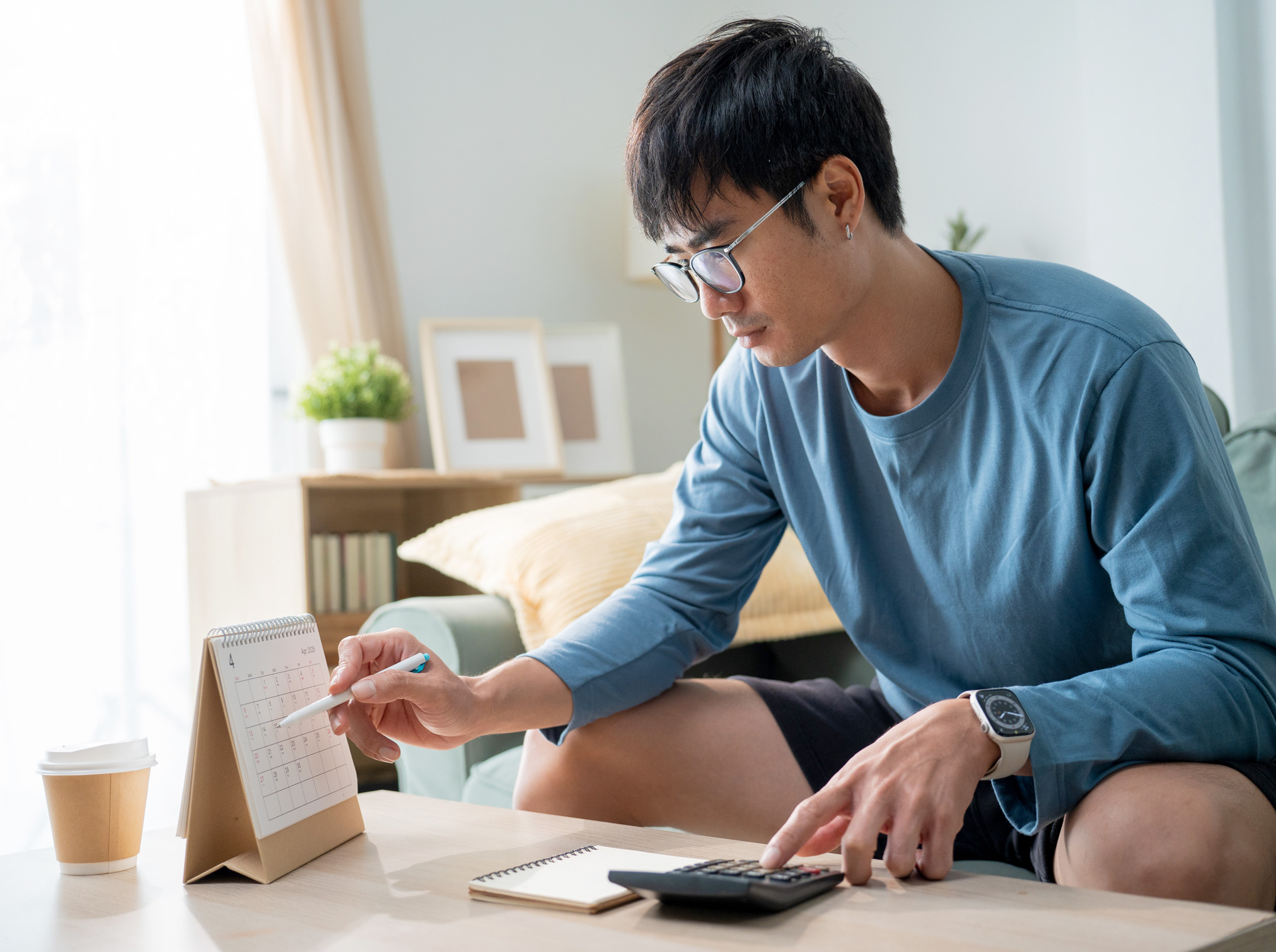 man looking at calendar and using calculator