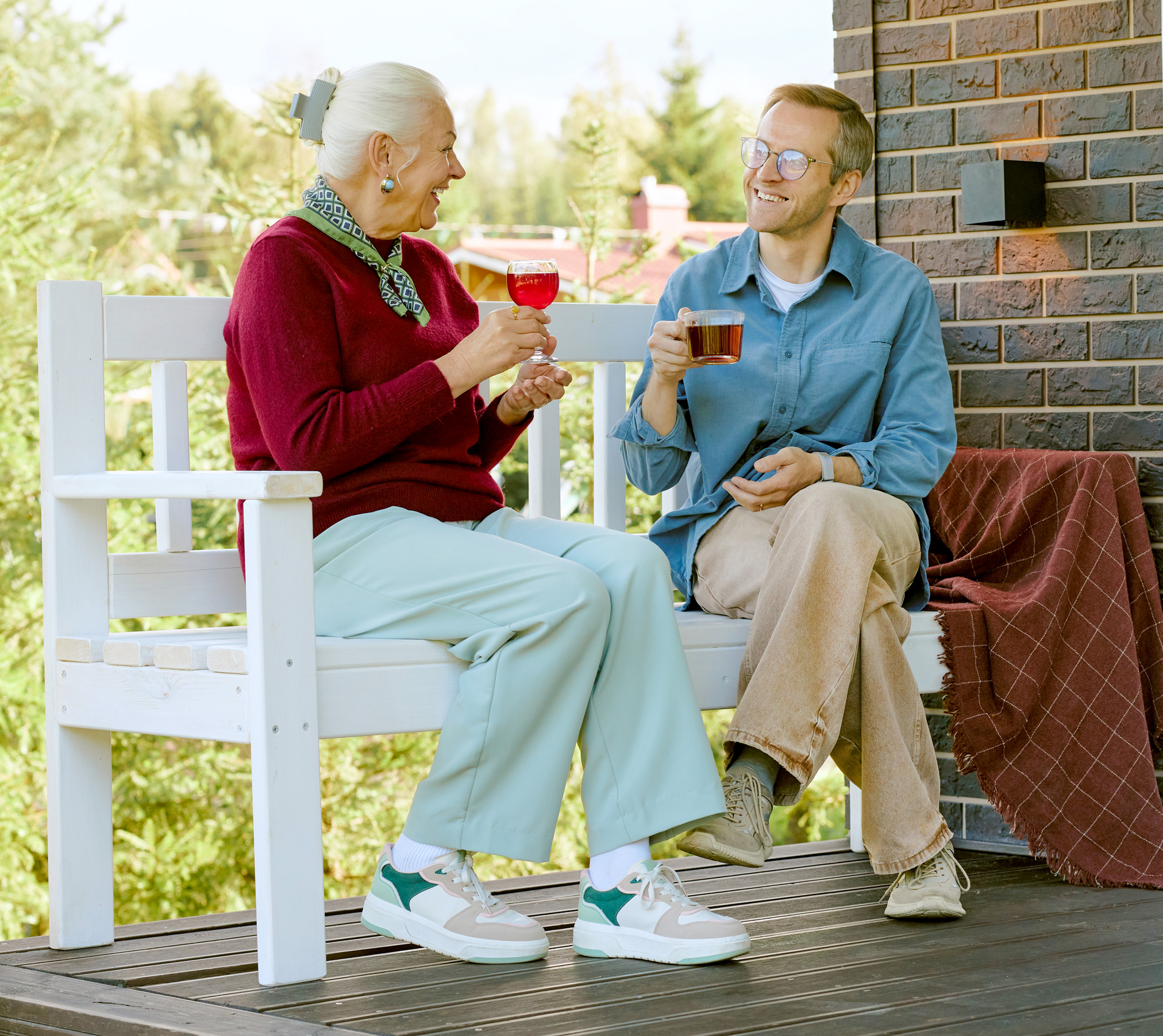Older woman drinking tea and chatting with younger man