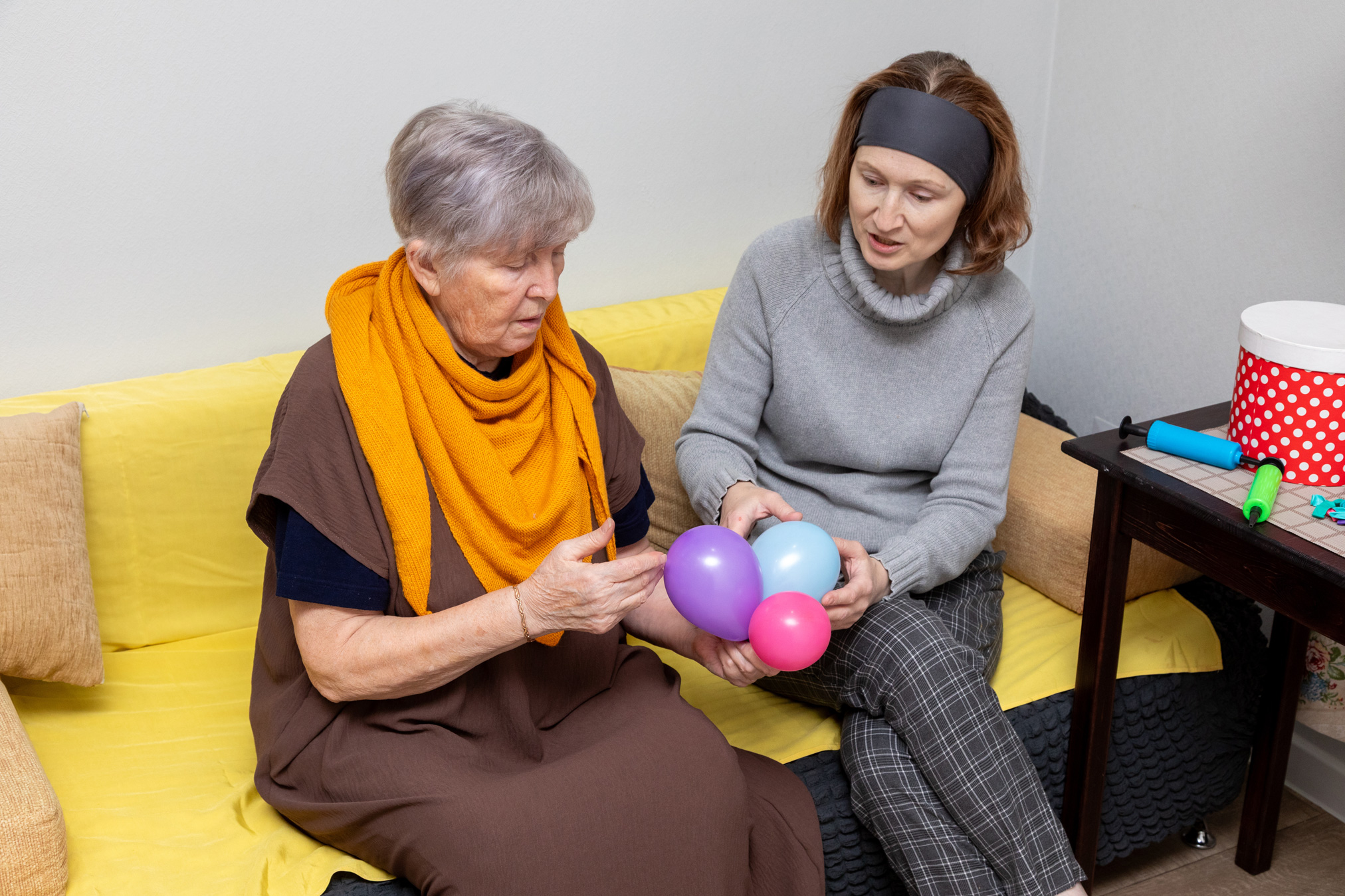 Older woman working with staff to construct a balloon bouquet