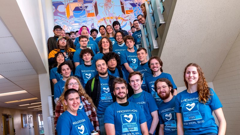 A large group of computer science club members in blue shirts on a staircase.