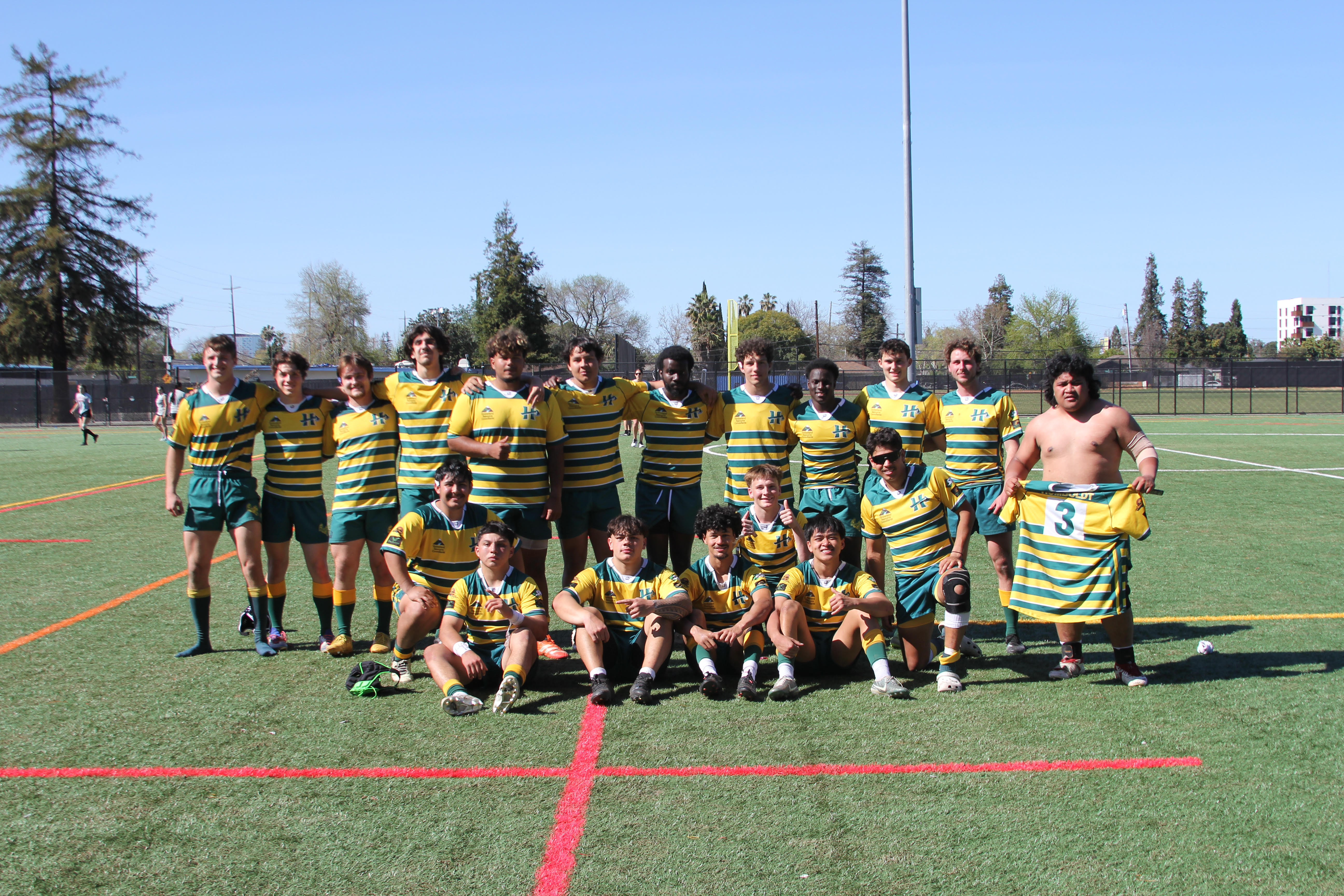 Team photo of the men's rugby club in yellow jerseys on the field.