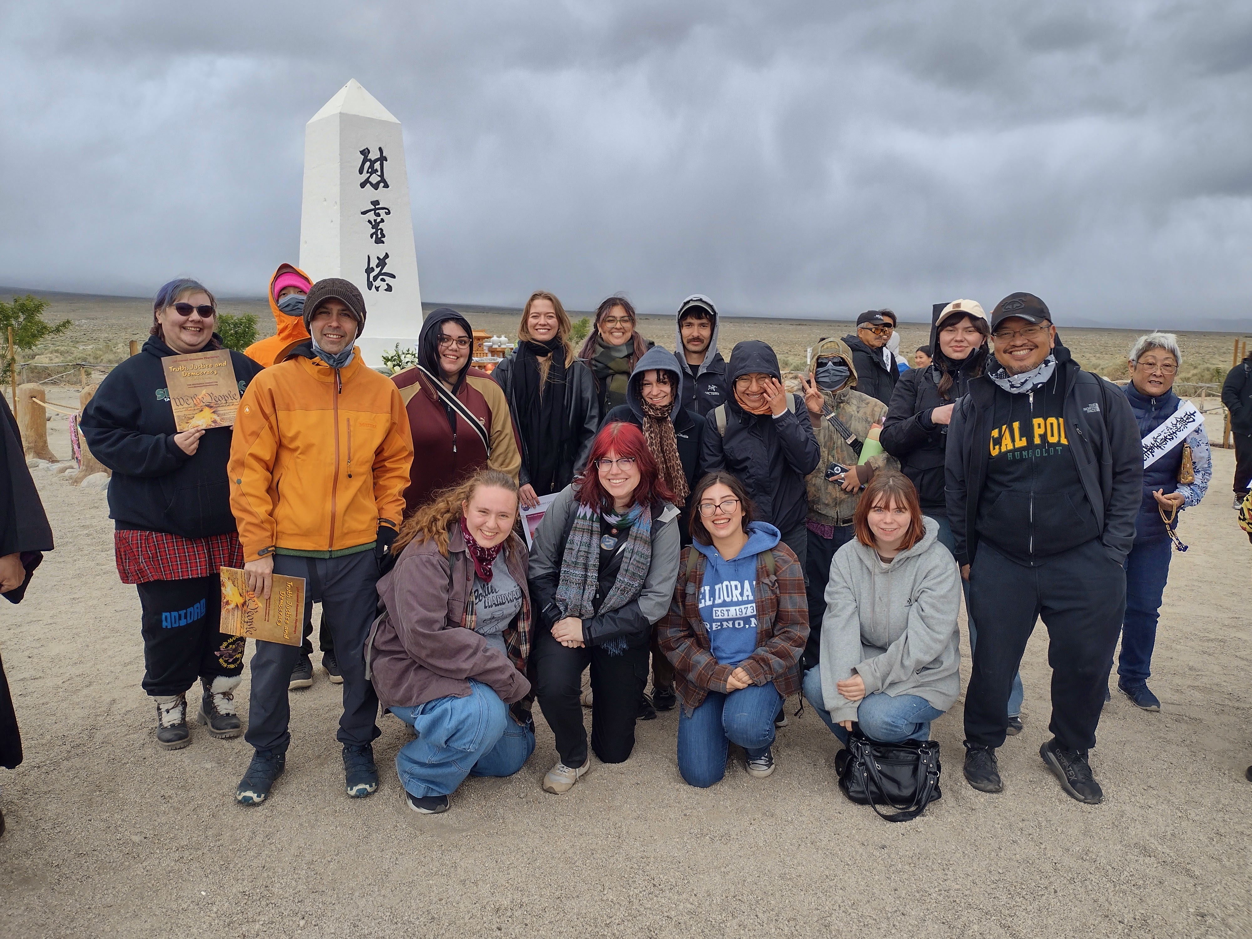 A group of sociology students posing together on a trip with a small monument in the background.