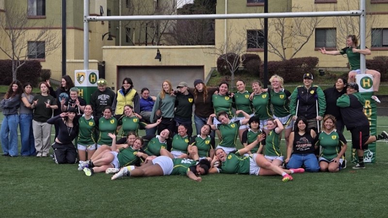 Humboldt women's rugby team in uniform posing in front of the goal posts on the field.