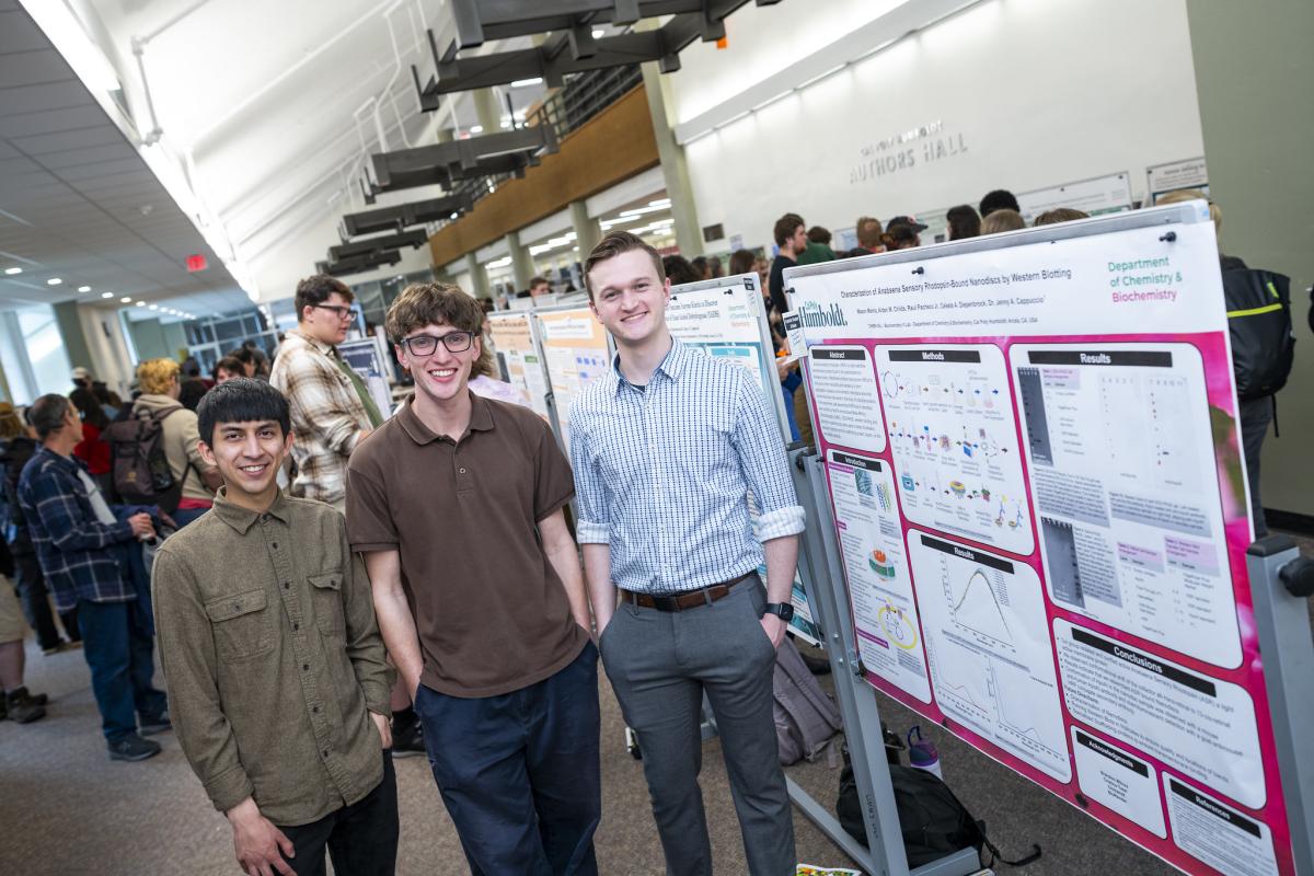 Three people standing in front of poster