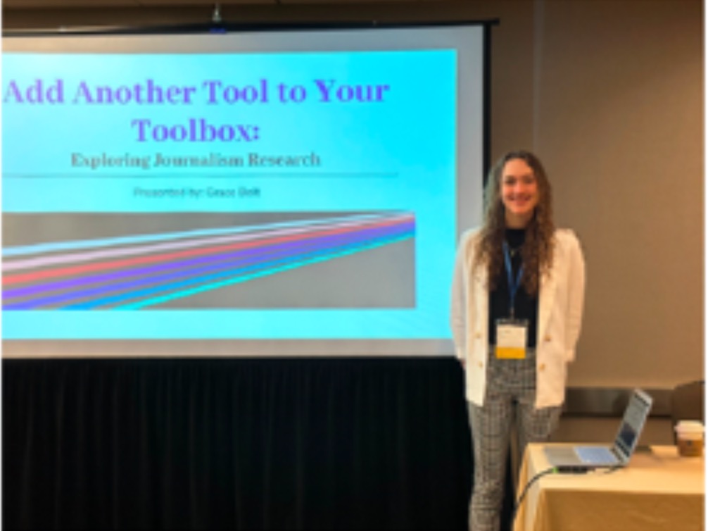 Grace standing next to a presentation screen