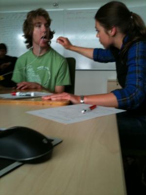 Student getting a tongue depressor put in their mouth