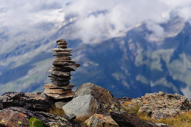 stack of rocks on the side of a cliff with clouds in the bakground