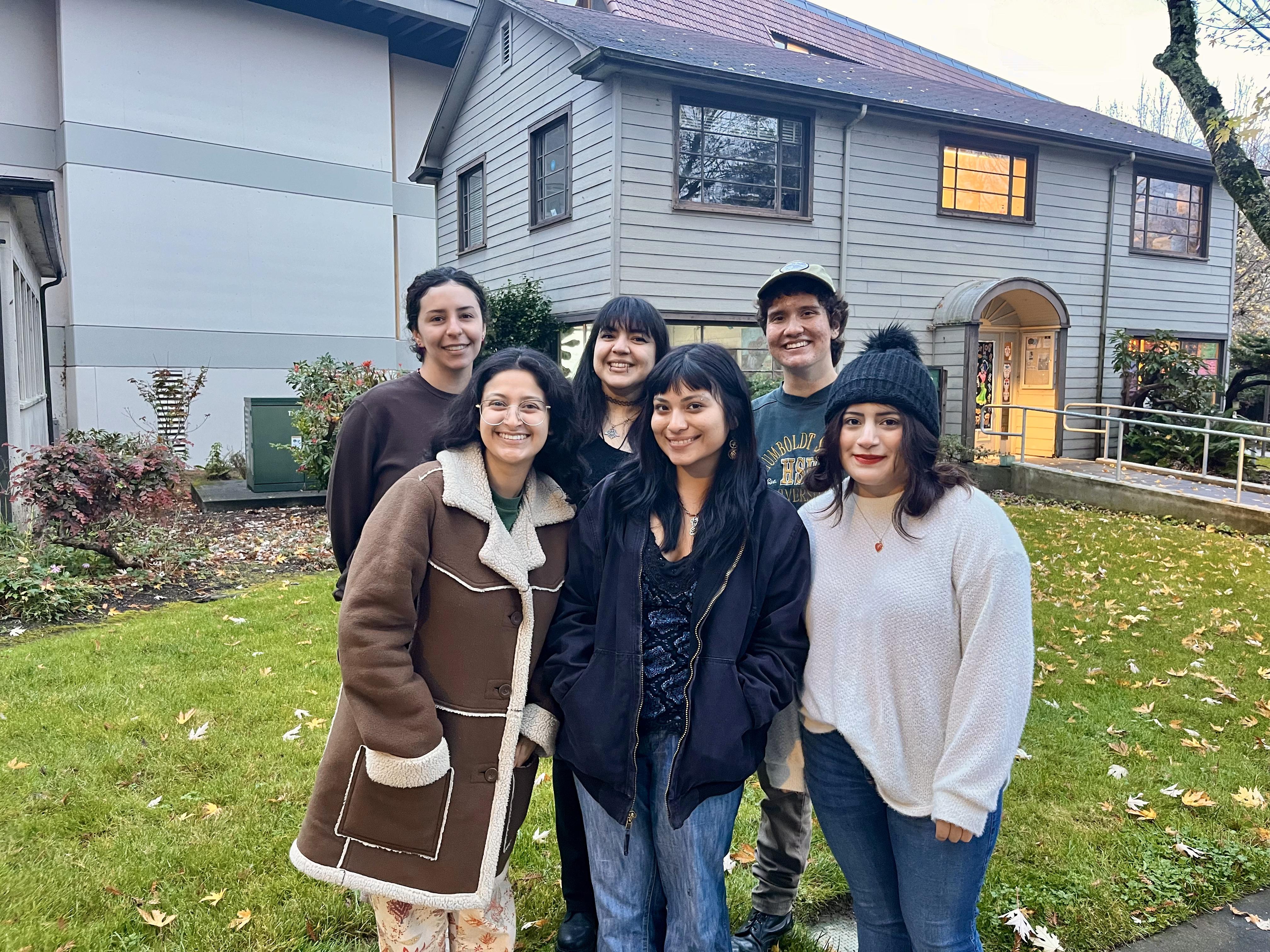 group of students standing in front of a house