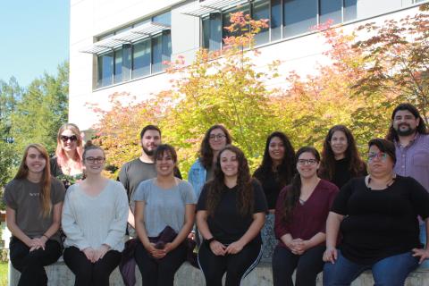 group of students sitting on a concrete wall in front of a campus building