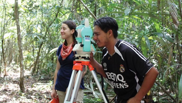 students in the forest looking through a piece of equipment