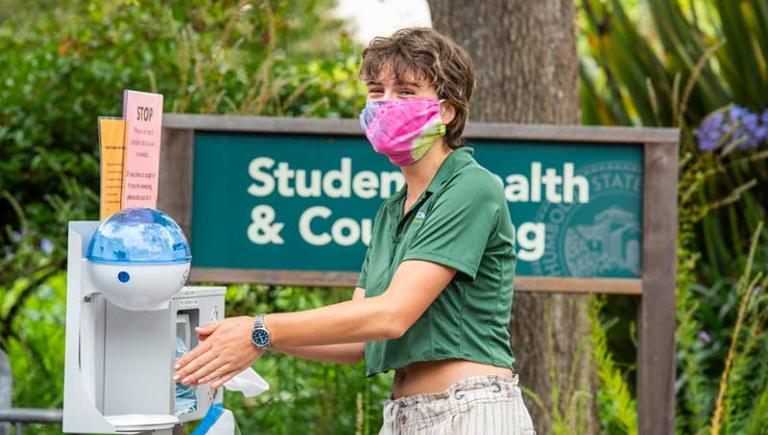 Student using hand sanitizer on campus