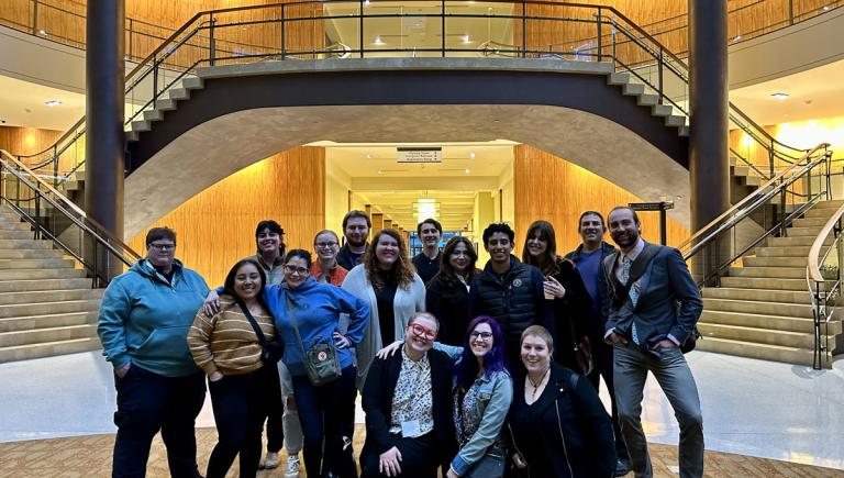 Students and faculty standing in front of a large staircase at the annual conference