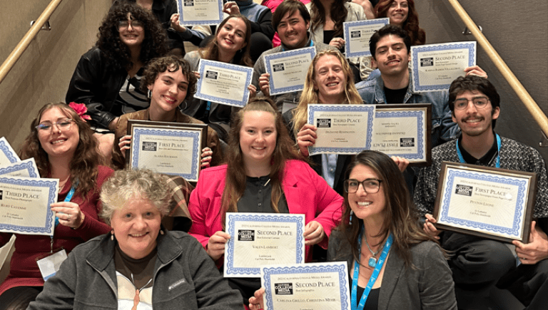 Students sitting on stairs holding certificates