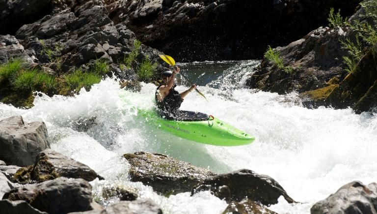 Green Kayak going over a large rapid. 