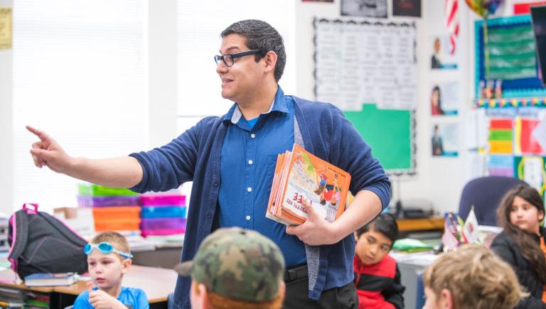 A student teacher holding some books talking to a class