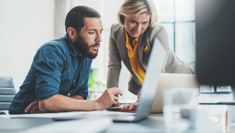 Man and woman discussing their work, with a computer