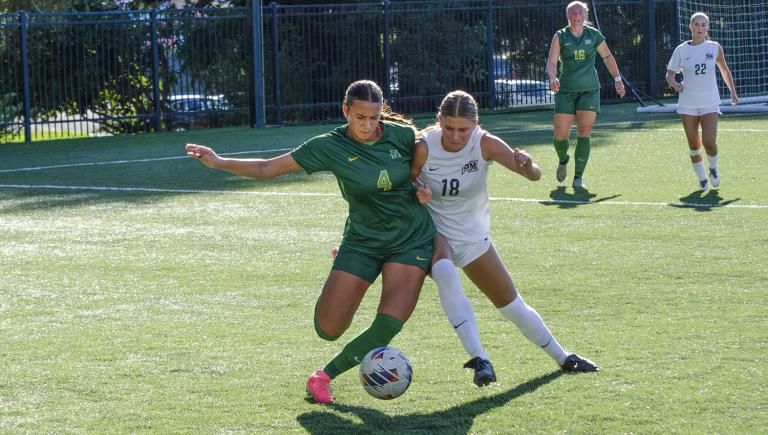 Humboldt women's soccer players in green uniforms competing against Cal State San Marcos players in white 