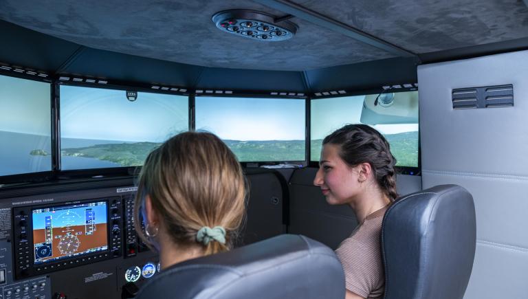 Two students practicing flight in the library flight simulator