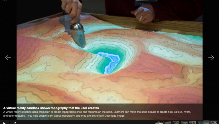 An overhead view of someone using the AR sandbox to display topography and watertable.