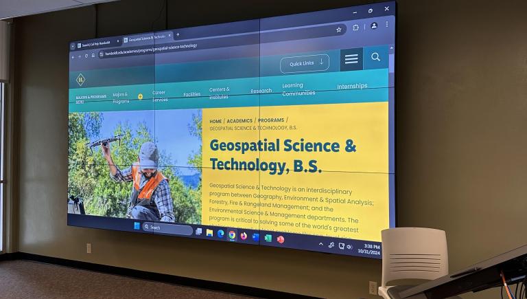 A side-on view of the digital video wall displaying the Geospatial department home website.
