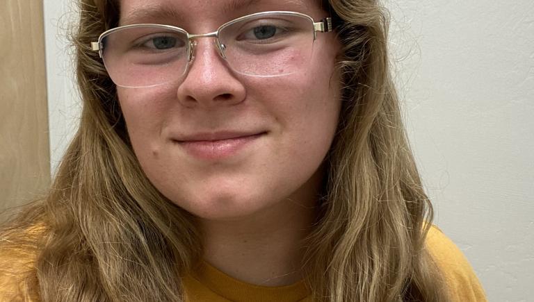 Student smiling in a yellow shirt