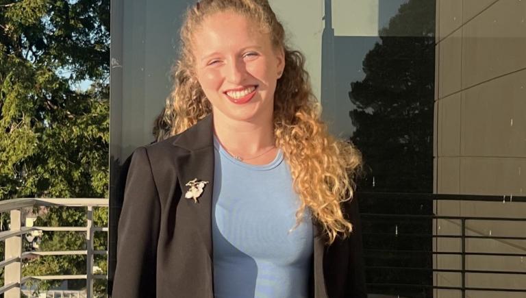 Student smiling in front of a window.