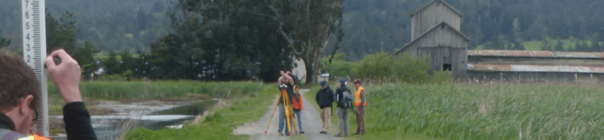 researchers surveying a site, next to an old barn