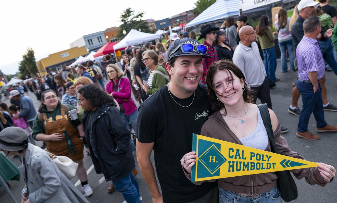 Two students who just received Cal Poly Humboldt swag at the Arcata Night Market 2025