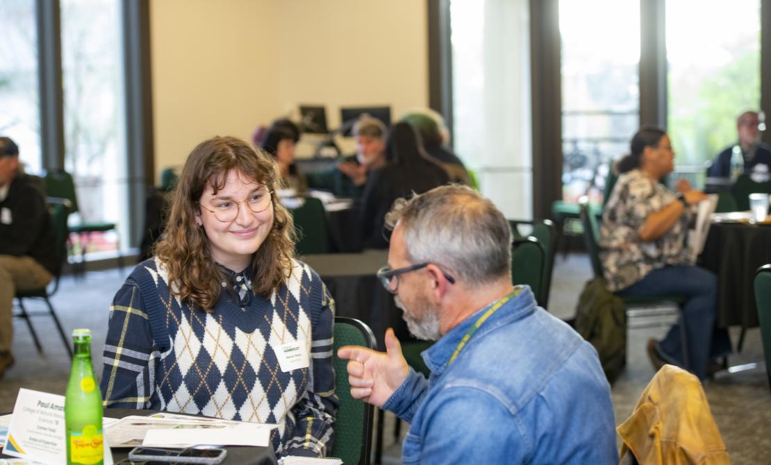 A student and an alumni at an Alumni Connections program. The two are discussing career opportunities and sharing knowledge.