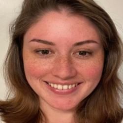 Person wearing a necklace and light colored shirt, with a white background