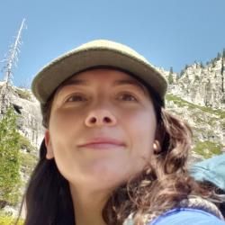 Person wearing a hat, with a mountain in the background