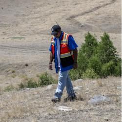 Person with a safety vest walking across a rocky landscape