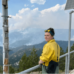 Person standing at a railing with mountains in the background