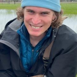 close up of Amida wearing a light blue beanie and outdoor gear