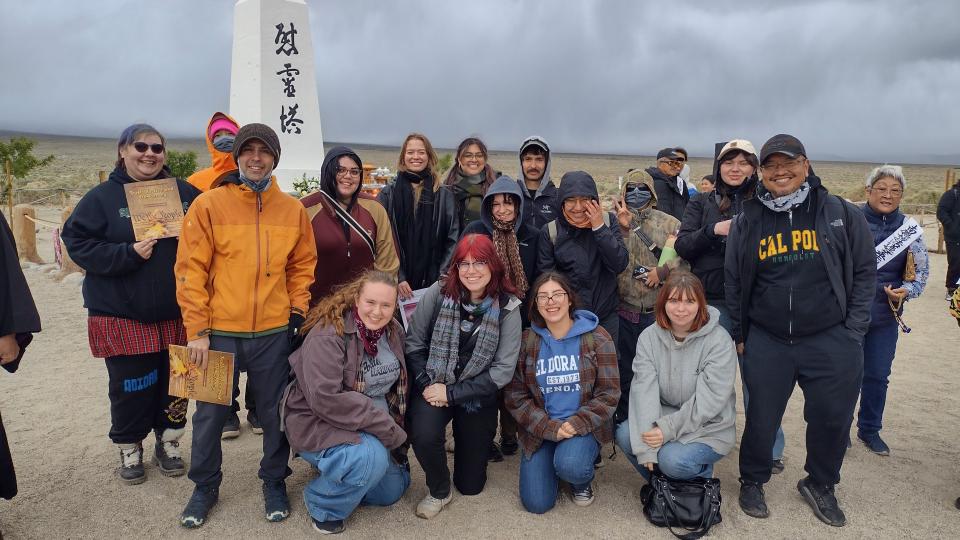 A group of sociology students posing together on a trip with a small monument in the background.