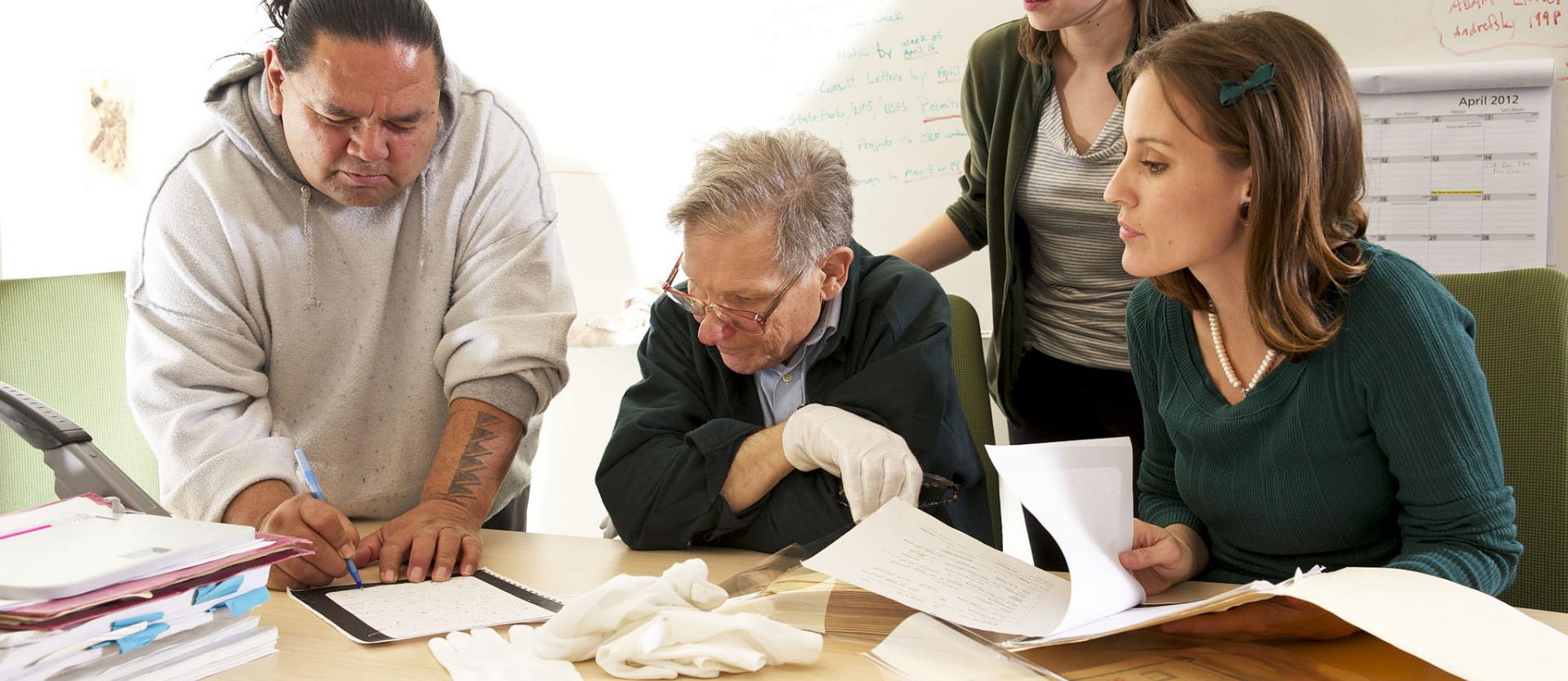 students and professor leaning over a table studying